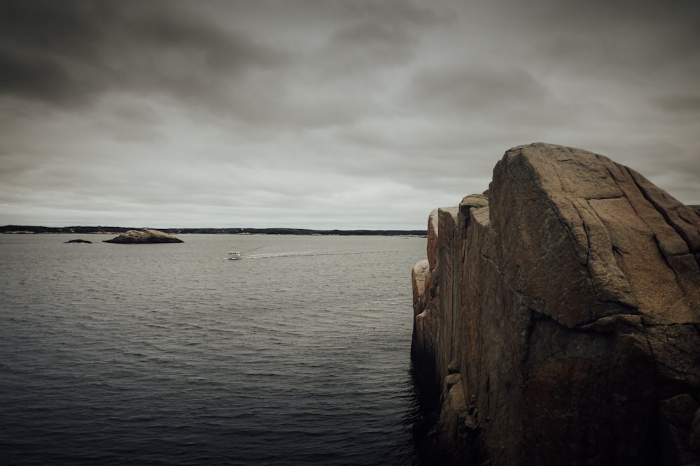 brown rock formation on sea under white clouds during daytime