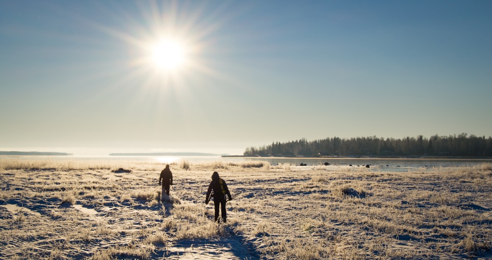 2 person walking on snow covered field during daytime