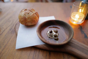 A rustic wooden table set with bowls of spicy sauces and freshly baked bread.