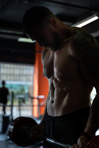 topless man in black shorts doing curl for biceps