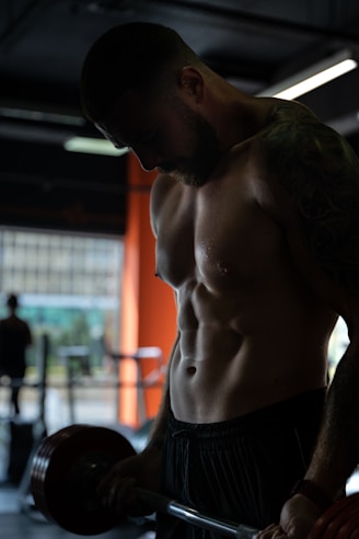 topless man in black shorts doing curl for biceps