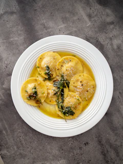 Top view of ricotta and spinach ravioli with a golden crust served on an elegant dark plate with subtle shadows