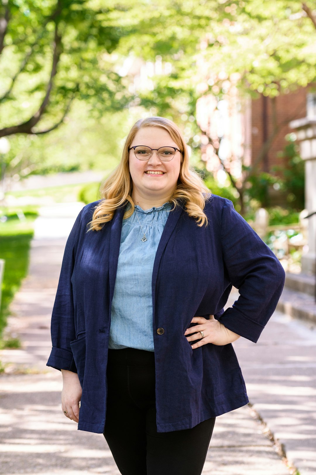 woman in blue coat standing near trees during daytime