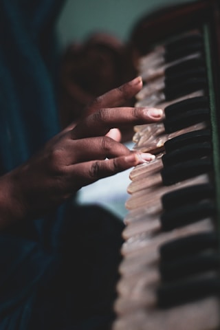 Close-up of Jairaj's hands gently holding a harmonium during a live performance.