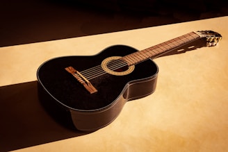 black acoustic guitar on white table
