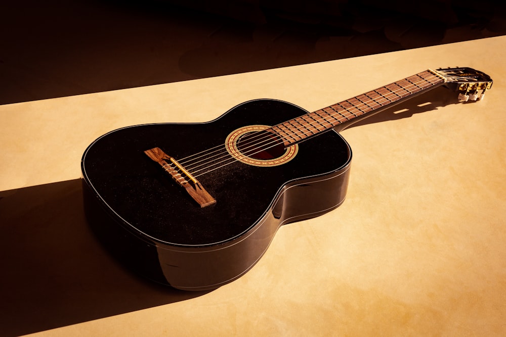 black acoustic guitar on white table