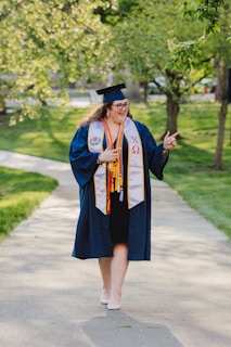 woman in blue academic dress standing on road during daytime