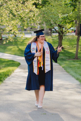 woman in blue academic dress standing on road during daytime