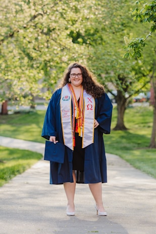 woman in blue academic dress standing on road during daytime