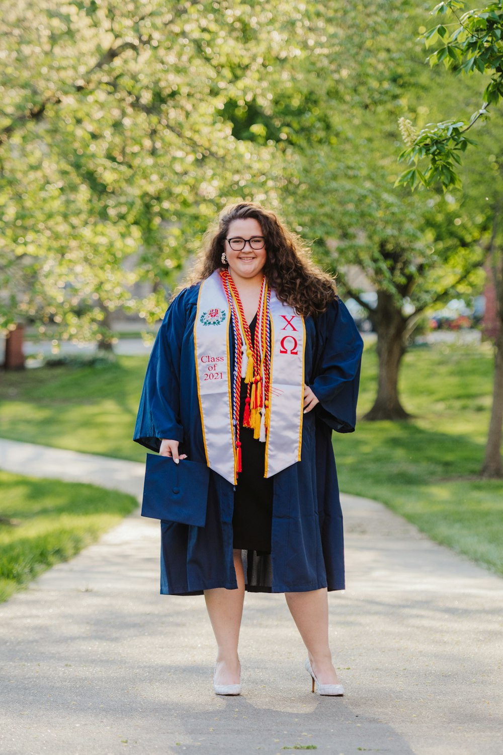 woman in blue academic dress standing on road during daytime