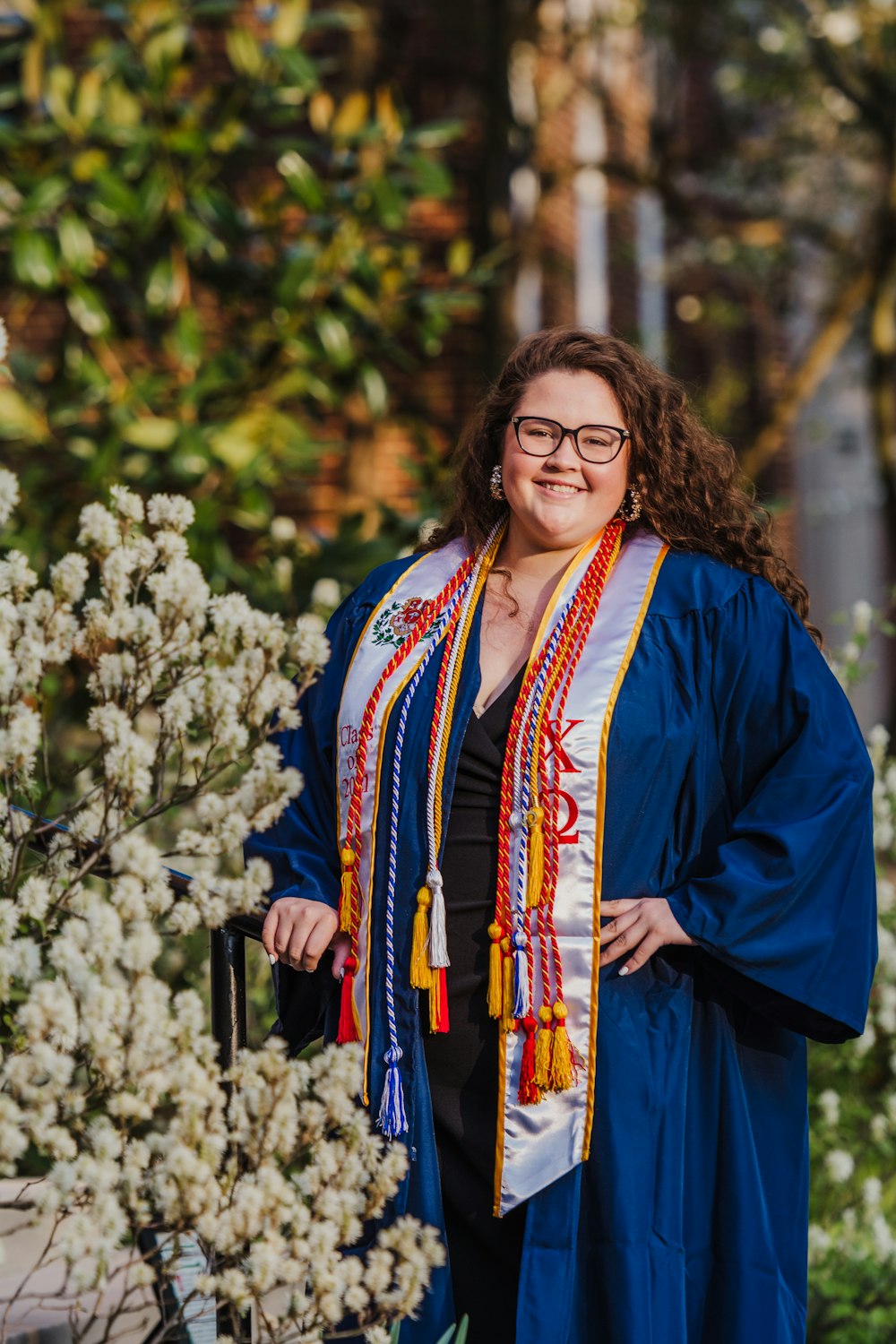 woman in blue coat standing near white flowers during daytime