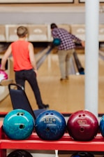 boy in orange t-shirt and black pants standing on blue and black exercise ball
