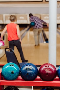boy in orange t-shirt and black pants standing on blue and black exercise ball