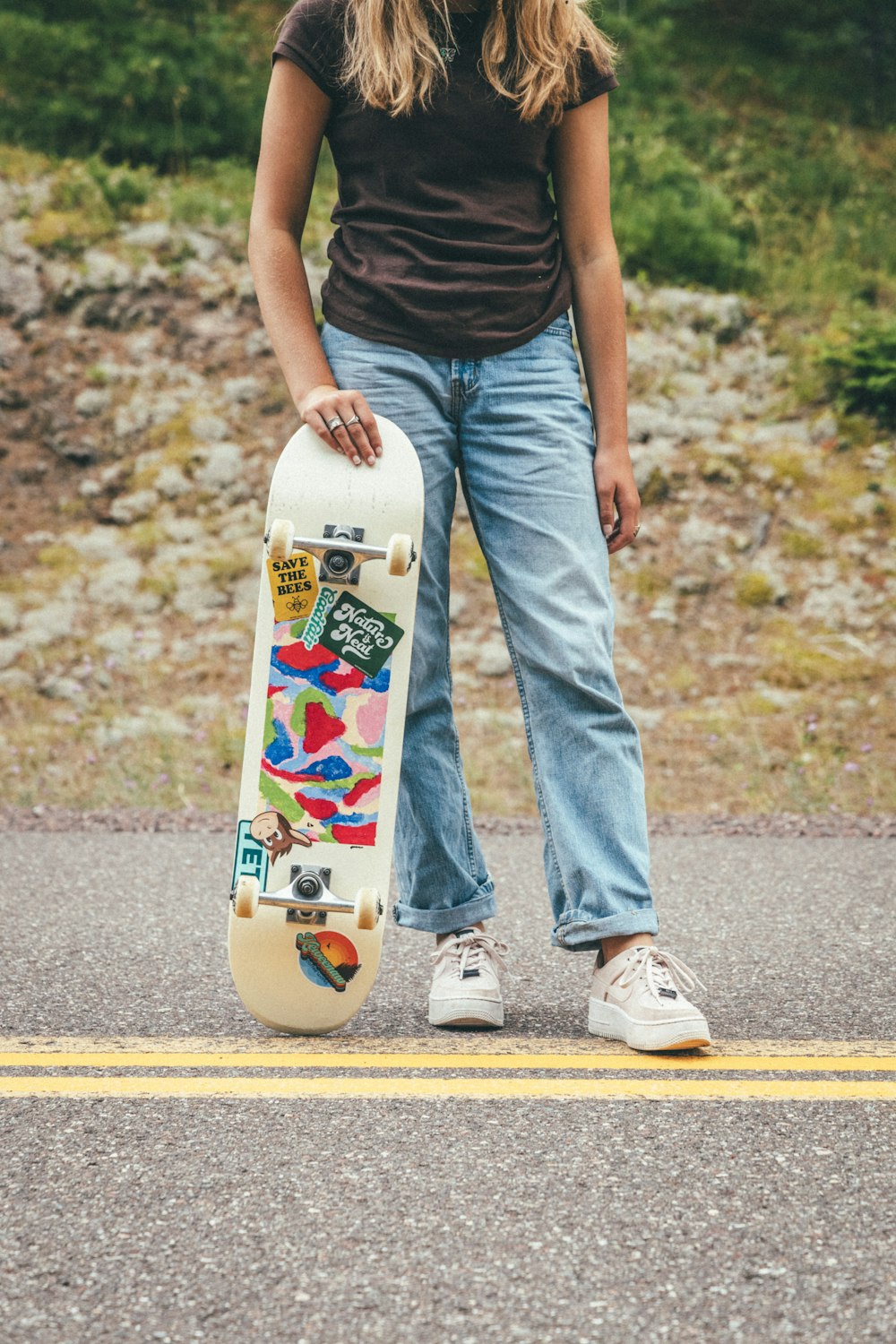 person in black tank top and blue denim jeans holding white and red skateboard