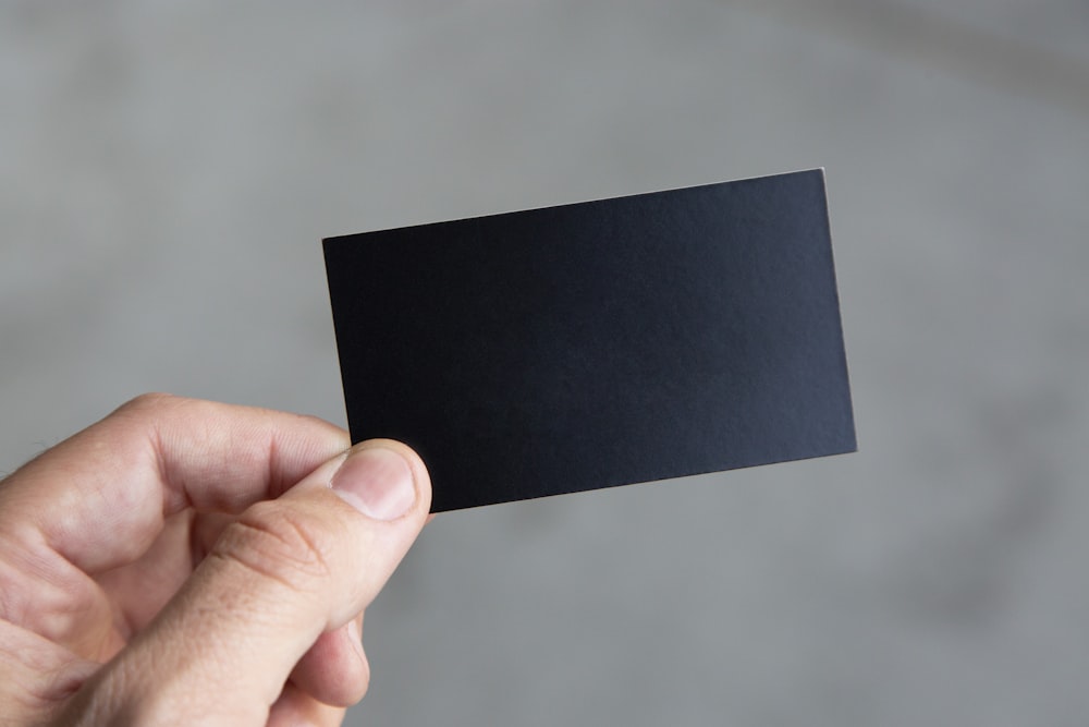 pessoa segurando papel retangular preto