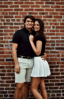 A happy young couple holding keys in front of their new first home, smiling warmly.