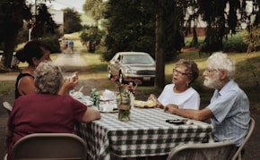 man in white crew neck t-shirt sitting on chair in front of table with food