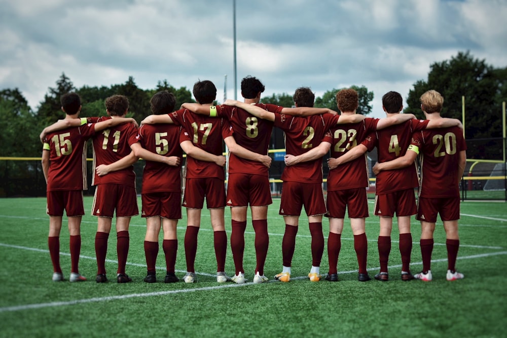 group of men in red and black jersey shirt and shorts standing on green grass field