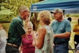 A joyful group of older adults sharing a lively outdoor workshop under warm sunlight.