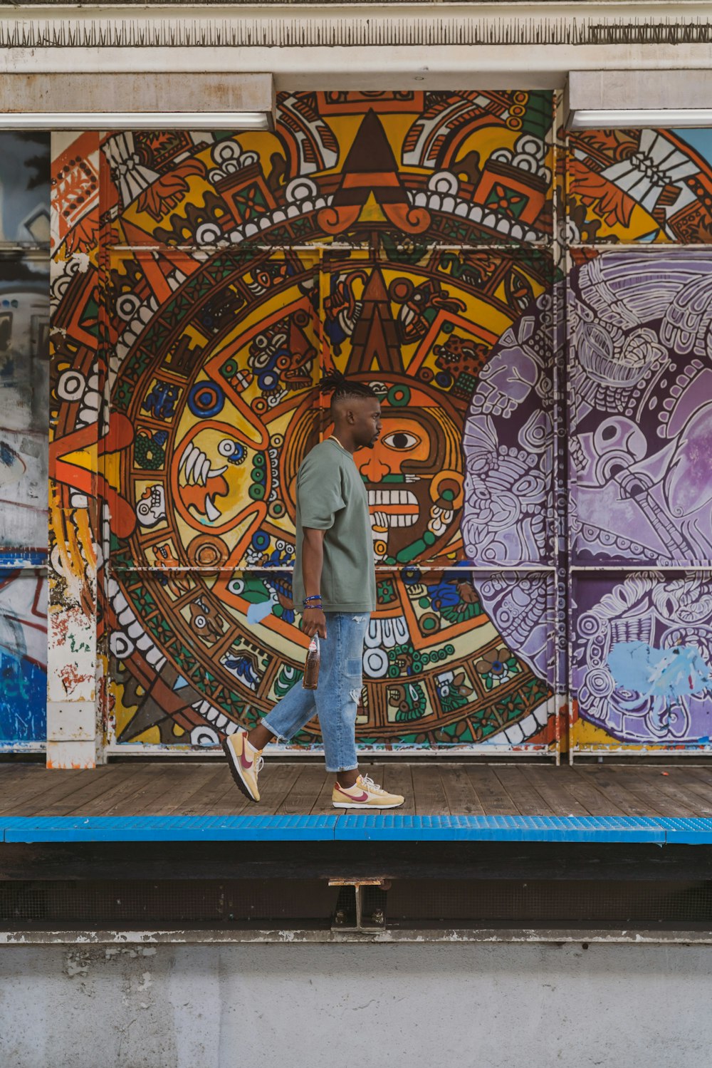 man in gray crew neck t-shirt standing beside wall with graffiti