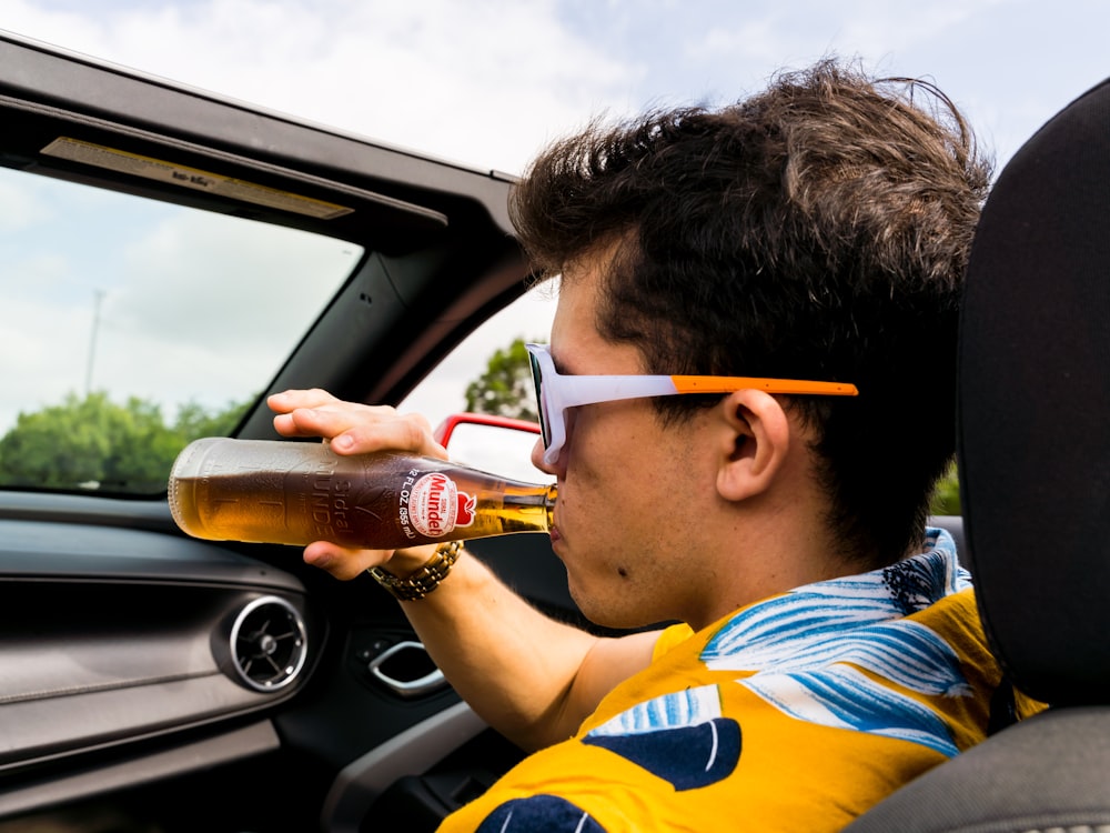 man in blue and yellow striped polo shirt drinking from bottle