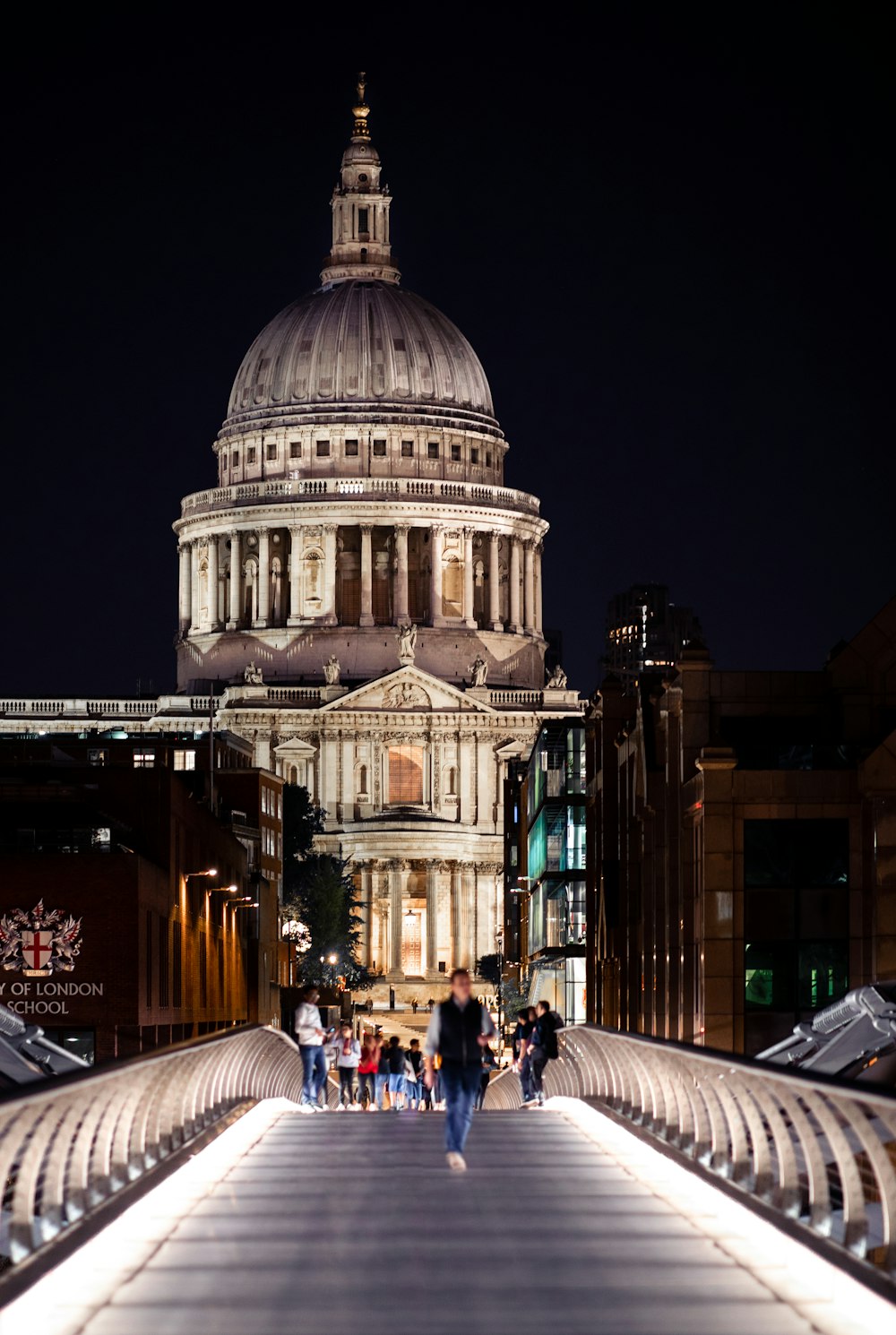 people walking on sidewalk near white concrete building during nighttime