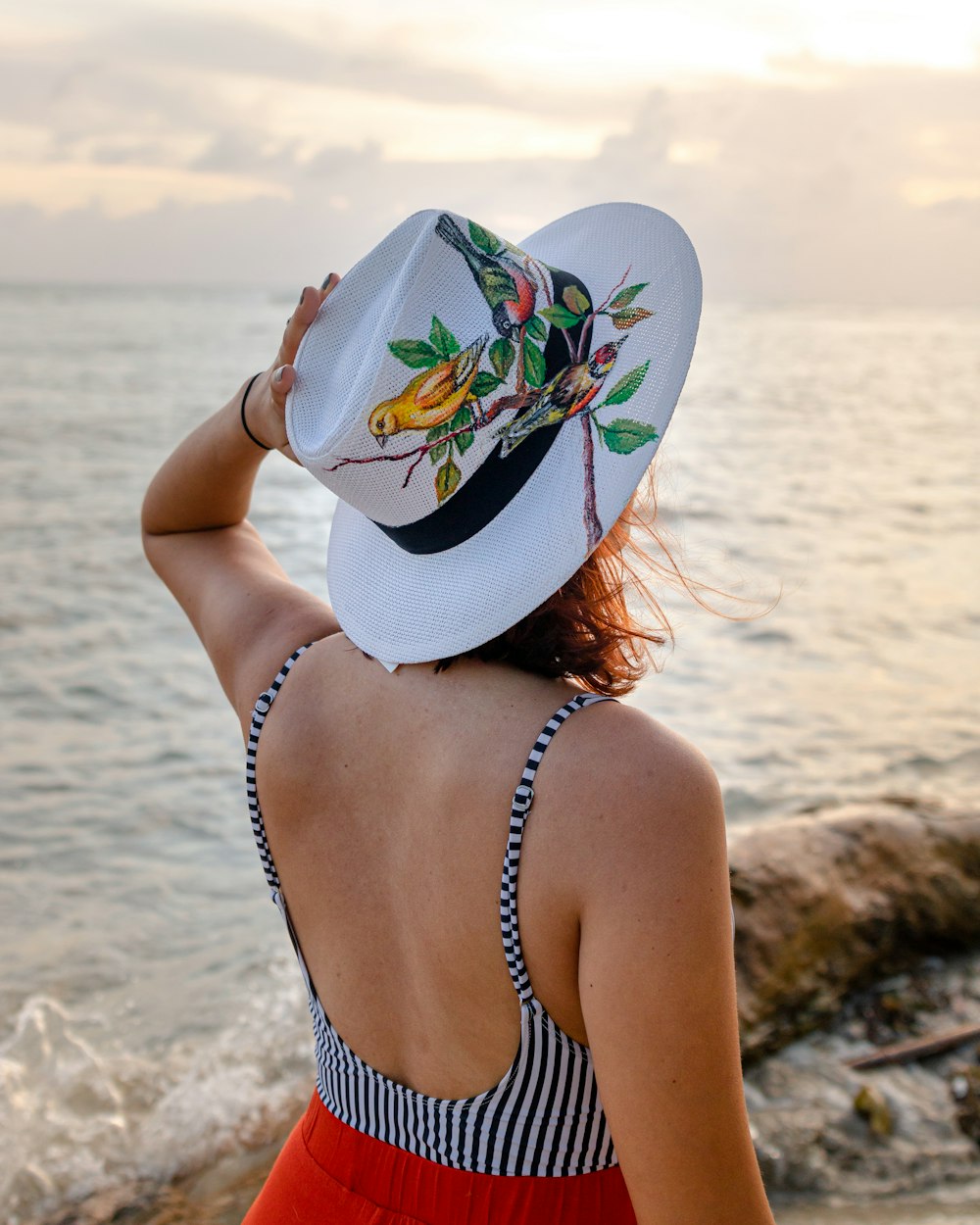 woman in white and blue floral sun hat on beach during daytime