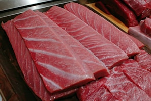 Fresh tuna slices neatly arranged on a clean white tray, showcasing quality and freshness