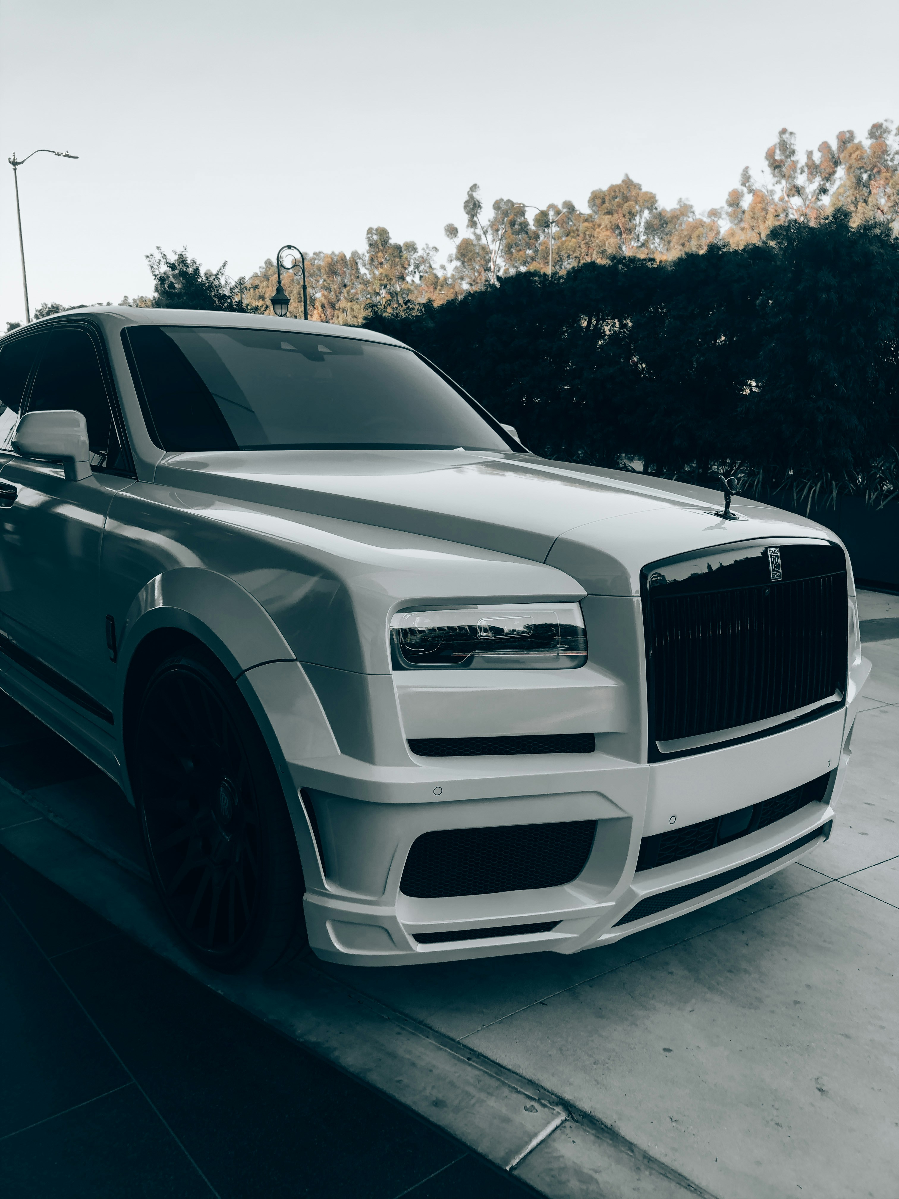 Rolls-Royce Cullinan in white, commanding SUV presence, dramatic night-time exterior lighting, Spirit of Ecstasy hood ornament visible