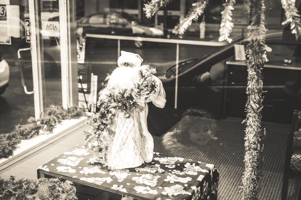 grayscale photo of woman in white dress standing near window