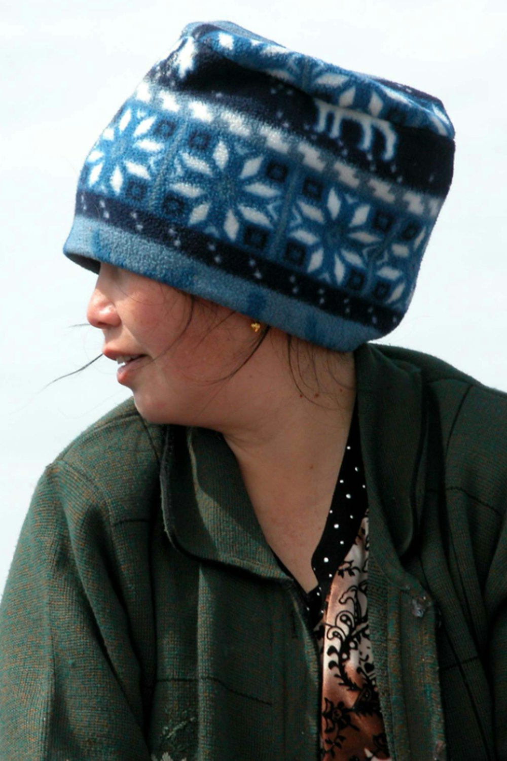 woman in green jacket wearing blue and white knit cap