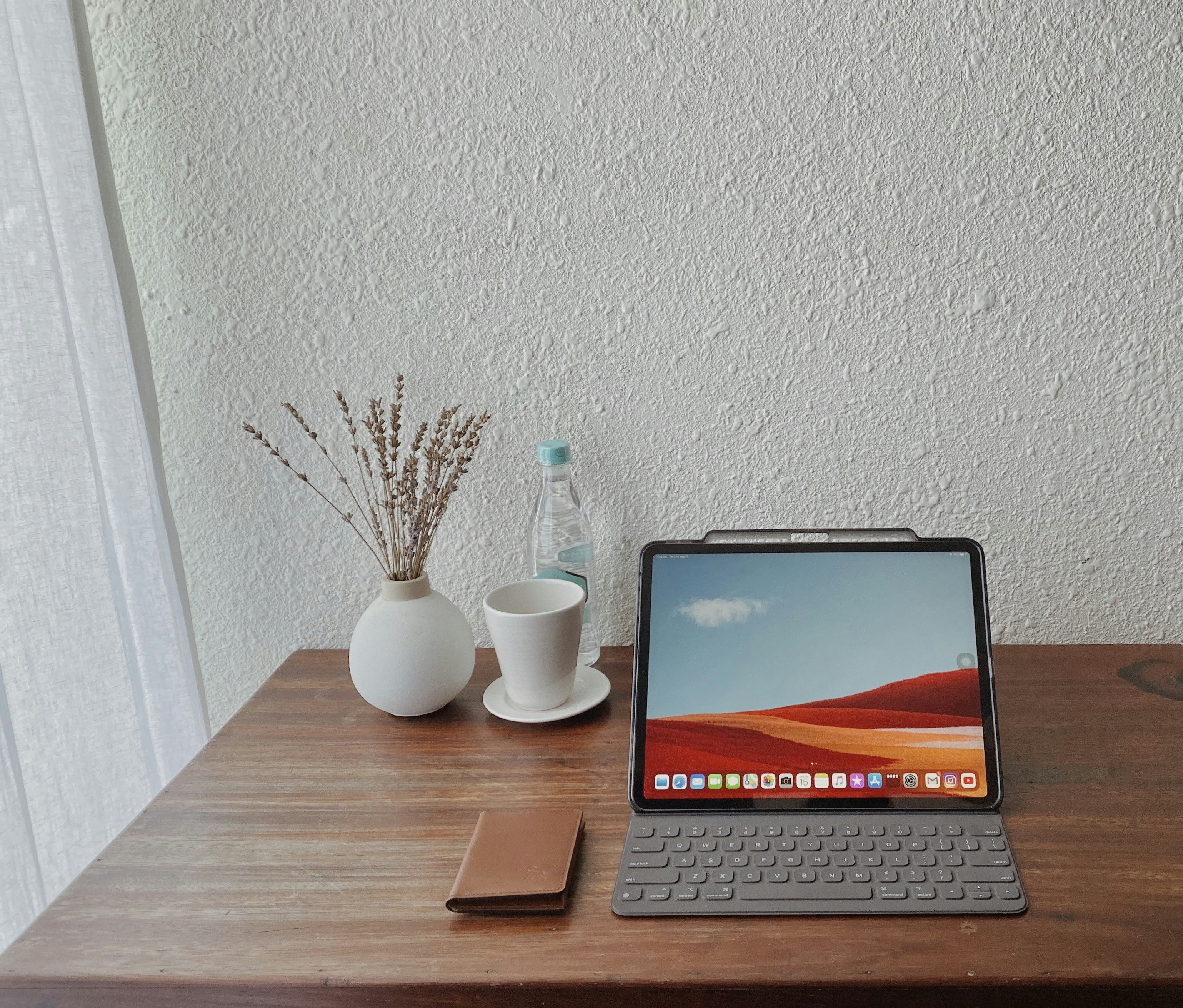 a minimalist wooden desk with a metallic iPad block projecting three floating holographic windows in mid-air