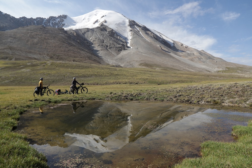 person riding on black motorcycle on green grass field near mountain during daytime