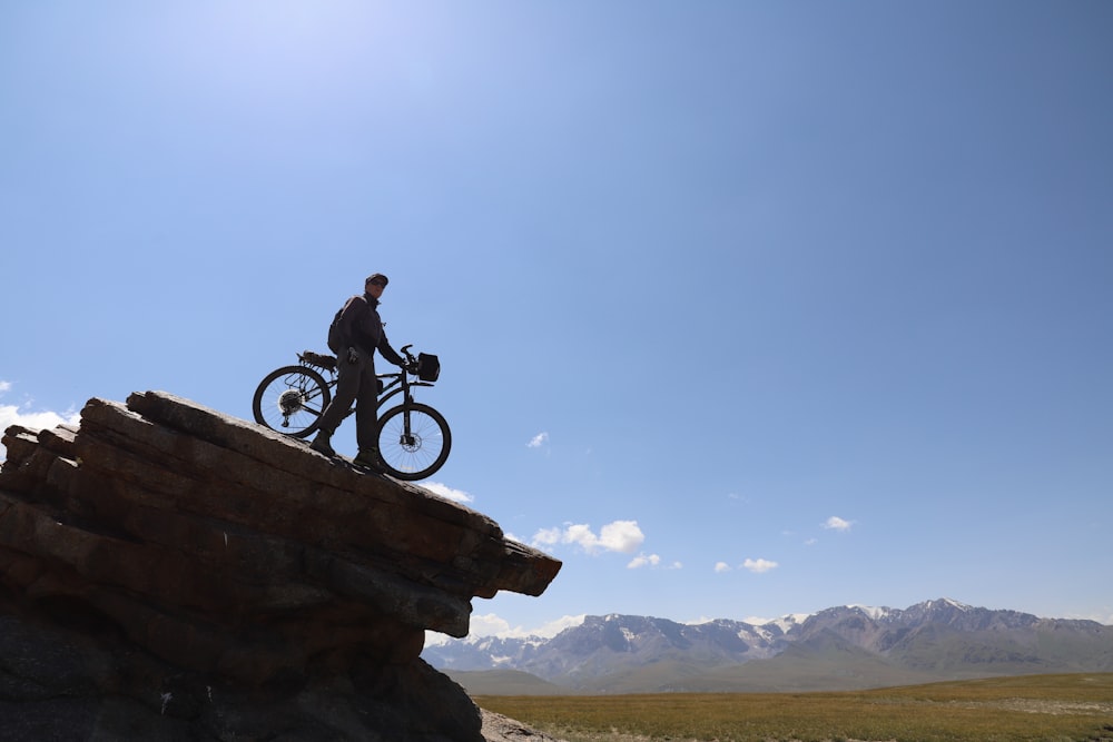 man riding bicycle on brown rock formation during daytime
