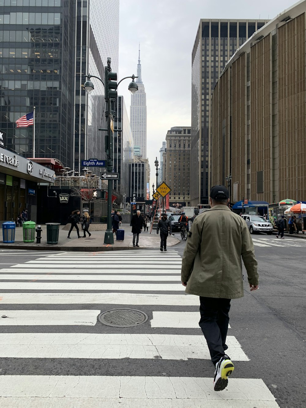 man in gray coat walking on pedestrian lane during daytime