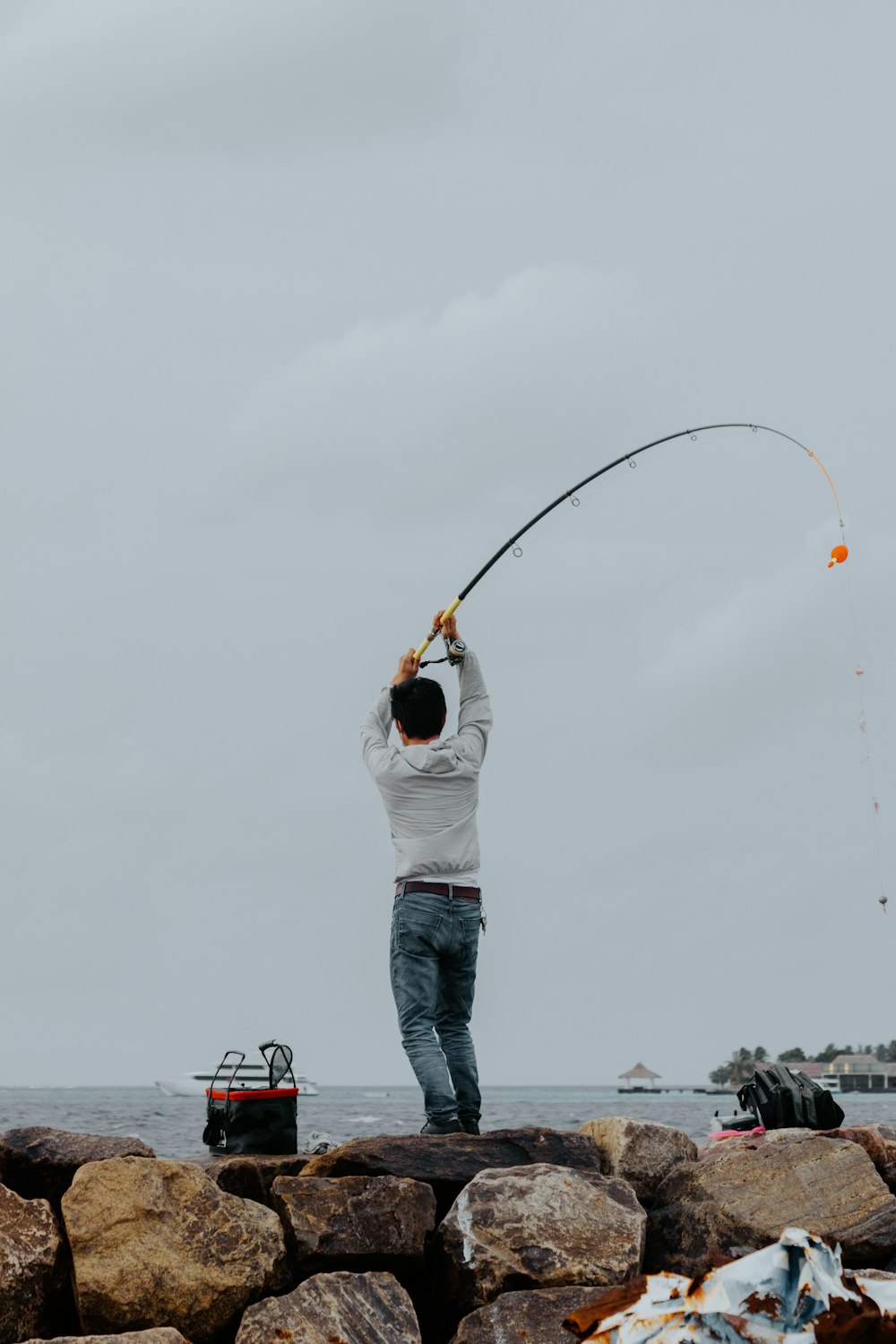 man in white long sleeve shirt and blue denim jeans holding fishing rod