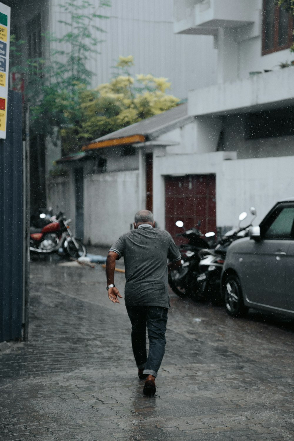 man in gray t-shirt and black pants standing beside black car during daytime