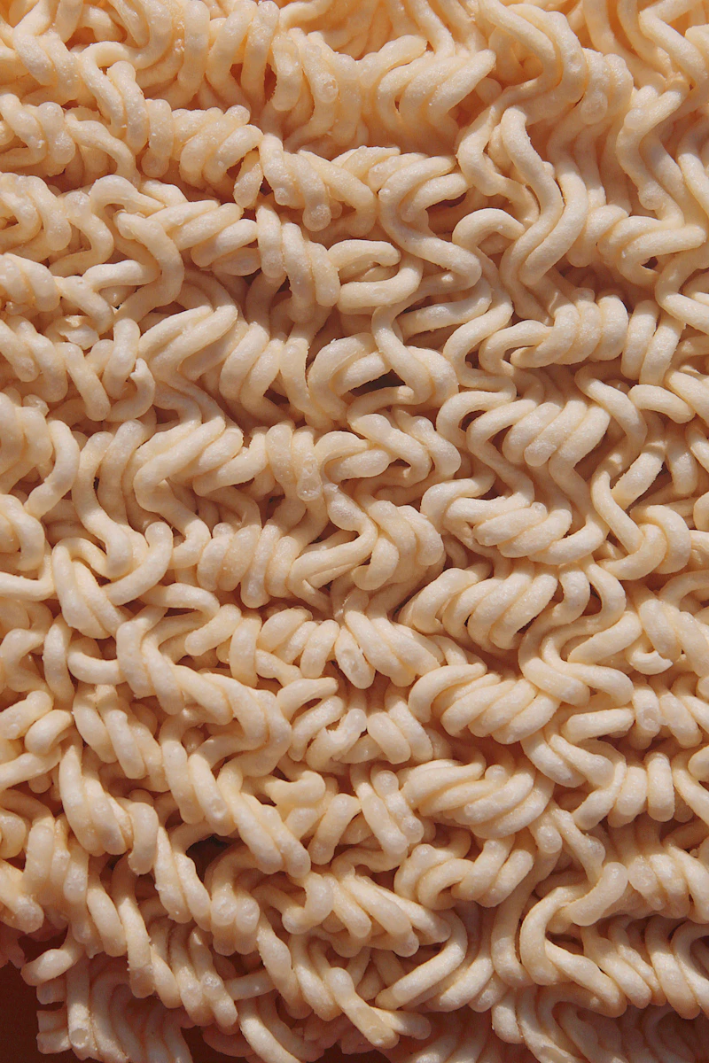 A single dried noodle strand on a pale surface — placeholder