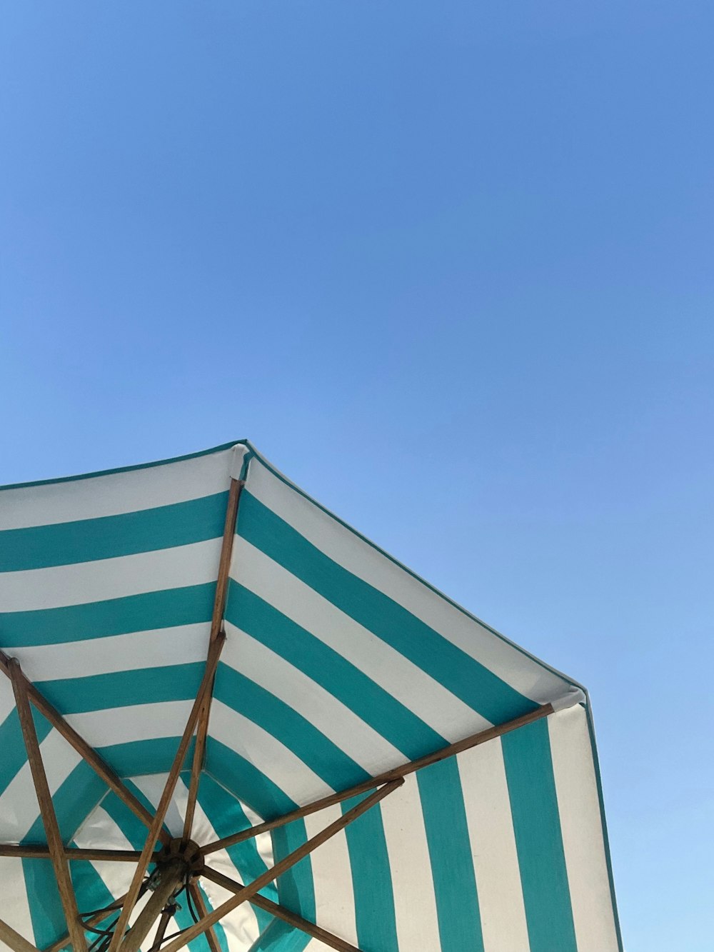 white and teal striped umbrella under blue sky during daytime