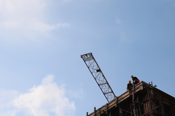 Construction workers in safety gear collaborating on a building site under a clear sky.