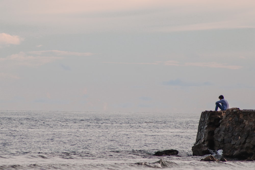 black rock formation on sea under white sky during daytime
