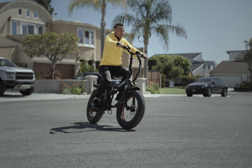 homme en chemise jaune conduisant une moto noire pendant la journée