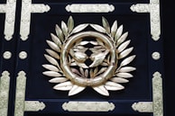 Close-up of an ornate family crest embossed in gold on dark green velvet fabric.