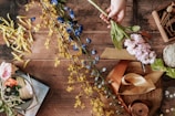 A rustic wooden table with various perfume bottles and flowers
