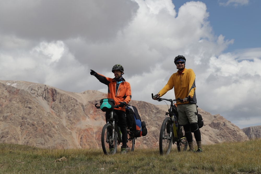 2 men in blue and orange shirt riding on bicycle during daytime