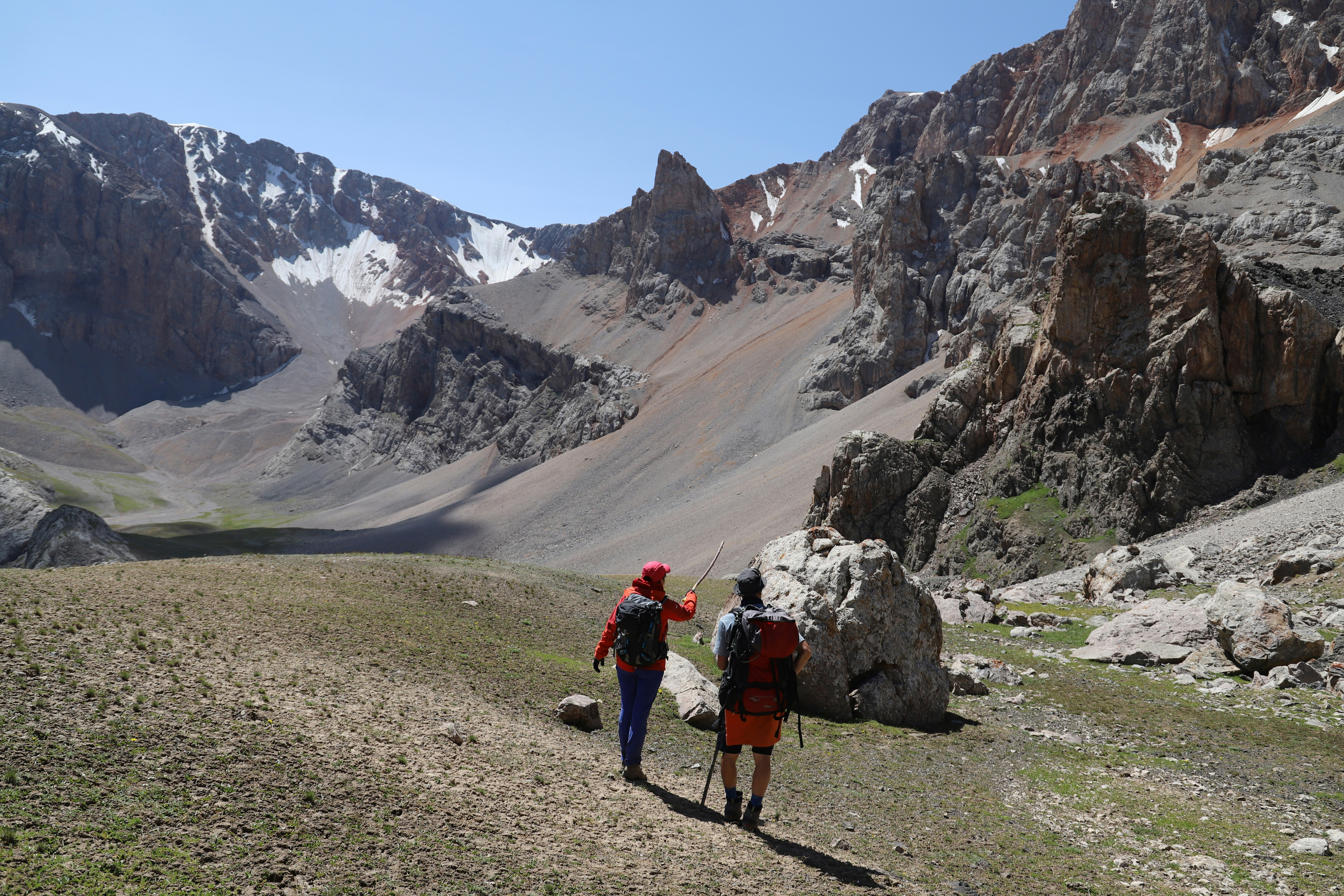 2 person walking on dirt road near mountain during daytime