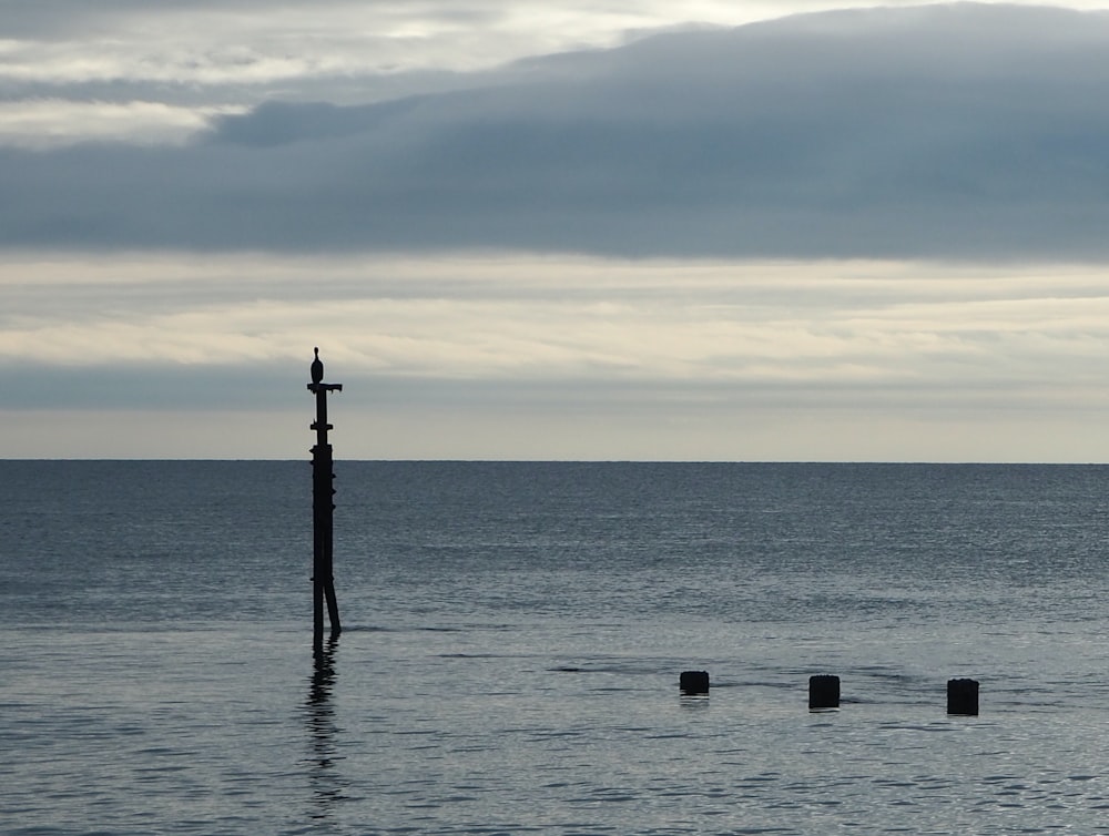 silhouette of post on sea during sunset