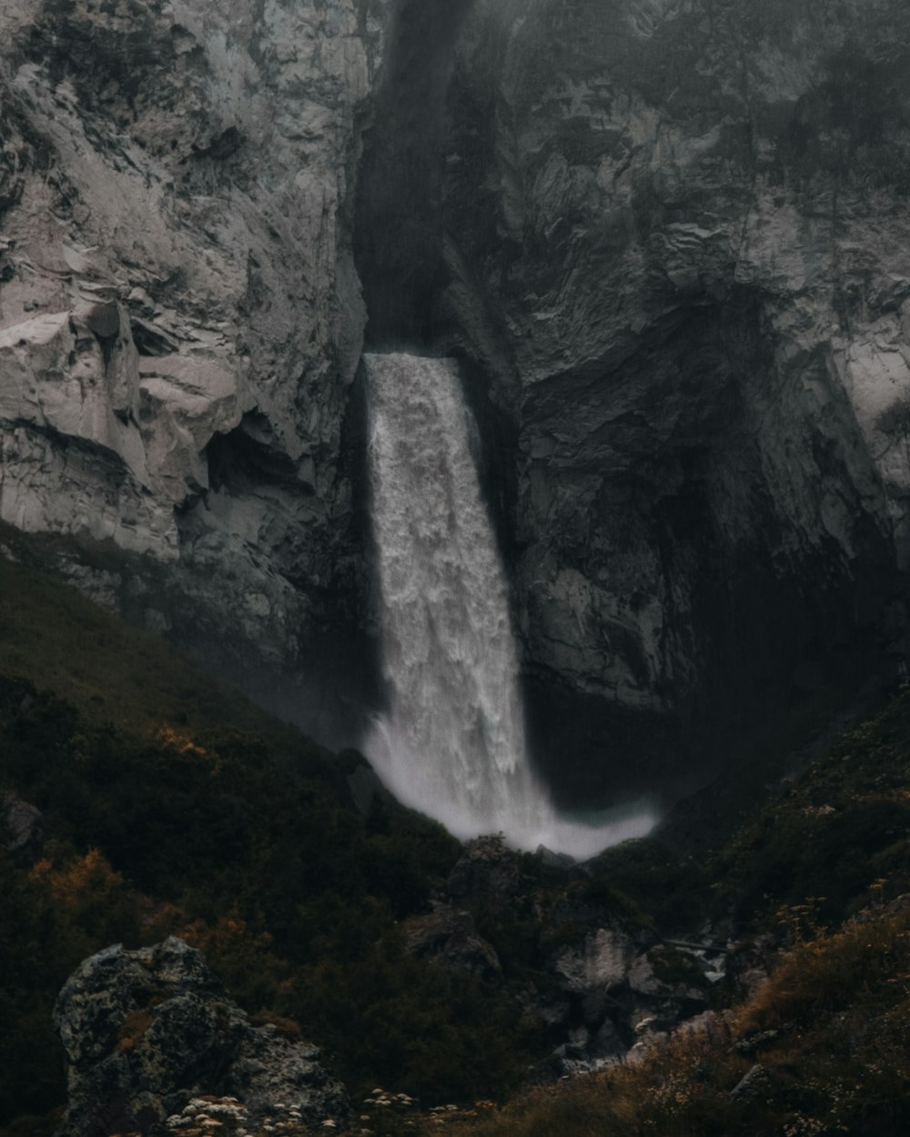 waterfalls between gray rocky mountain during daytime