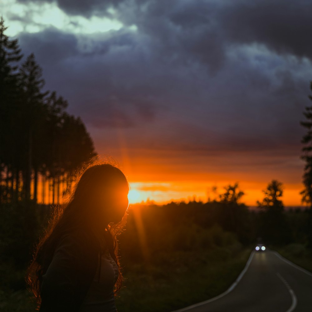 silhouette of woman sitting on ground during sunset