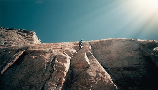 Climber scaling a textured limestone wall bathed in warm morning light at the Jilotepec cliffs.